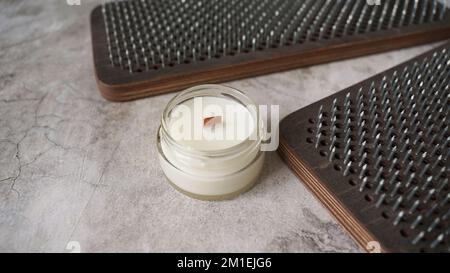 Sadhu-Bretter zum Stehen auf Metallnägeln mit hausgemachter Kerze. Yoga- und Meditationspraxiskonzept Stockfoto