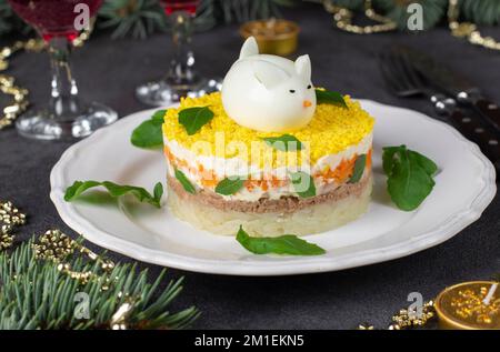 Puffsalat Mimosa für das neue Jahr mit Thunfischkonserven, Kartoffeln und Karotten, dekoriertem Häschen aus Ei Stockfoto