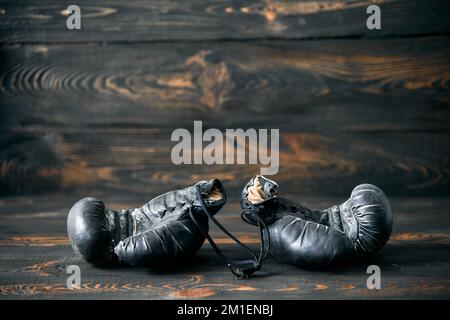 Alte Boxhandschuhe auf Holzhintergrund. Sport. Altersvorsorgekonzept Stockfoto