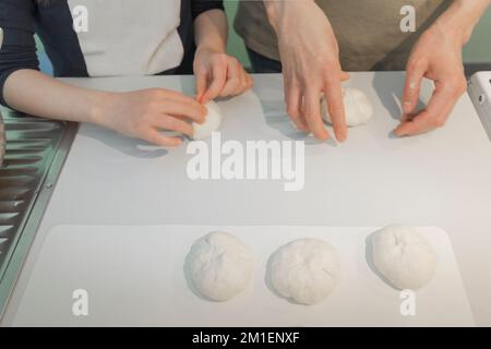 Erste Erfahrung in der Küche. Mom lehrt Tochter, wie man Kuchen macht Stockfoto