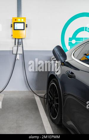 Elektroautos werden von der Ladestation in der Parkgarage des Einkaufszentrums geladen Stockfoto