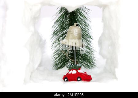 Weihnachtswagen mit Schneeglocke, hinter dem Auto befindet sich ein Weihnachtsbaum, kreatives Weihnachtsdesign Stockfoto