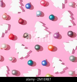 Eine 3D-Wiedergabe des trendigen Weihnachtsmusters mit farbenfrohen Kugeln und Weihnachtsbäumen auf pinkfarbenem Hintergrund, das Konzept des Neujahrs Stockfoto