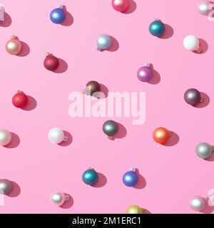Eine 3D-Wiedergabe des trendigen Weihnachtsmusters mit farbenfrohen Kugeln und Schatten auf pinkfarbenem Hintergrund, das Konzept des Neujahrs Stockfoto