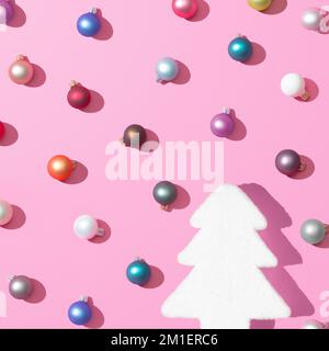 Eine 3D-Wiedergabe des trendigen Weihnachtsmusters mit bunten Kugeln und einem Weihnachtsbaum auf pinkfarbenem Hintergrund, dem Konzept des Neujahrs Stockfoto