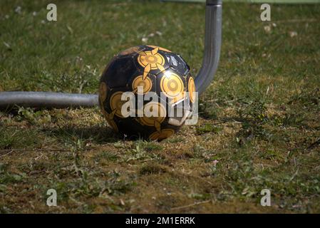 A closeup shot of ripped black and yellow football on a grass field after the big game Stockfoto