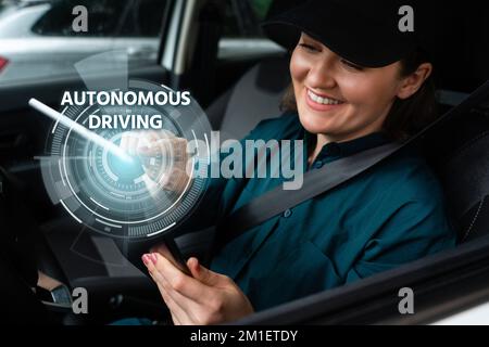 Weibliche Fahrerin steuert ein autonomes Auto mit einem Smartphone Stockfoto