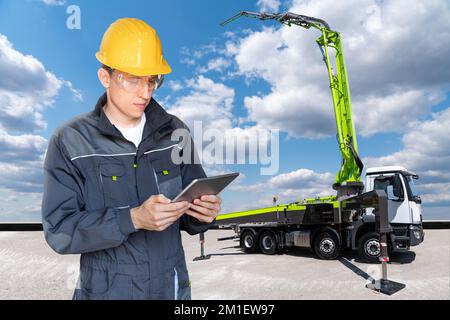 Ingenieur mit digitalem Tablet auf einem Hintergrund einer auf Lkw montierten Betonpumpe Stockfoto