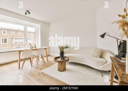 Ein Wohnzimmer mit Couch, Tisch und Fenster mit Blick auf die Straße vor den Fenstern des Apartments Stockfoto