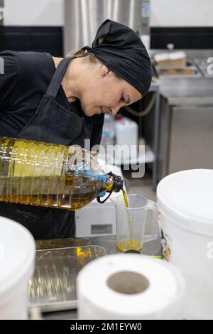Chefkoch, der Olivenöl in der professionellen Küche misst Stockfoto