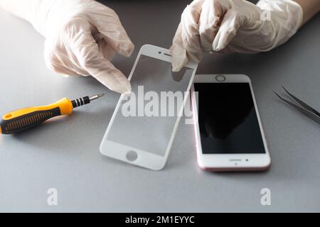 Smart Solution Technologiekonzept. Zugeschnittener Fotoersatz von Schutzfolie durch einen neuen. Man entfernt vorsichtig das alte Schutzglas aus dem Stockfoto