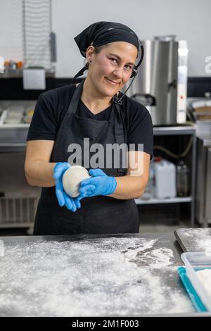 Professionelle Chefköchin, die Brotteig knete Stockfoto