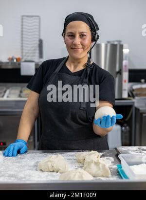 Professionelle Chefköchin, die Brotteig knete Stockfoto