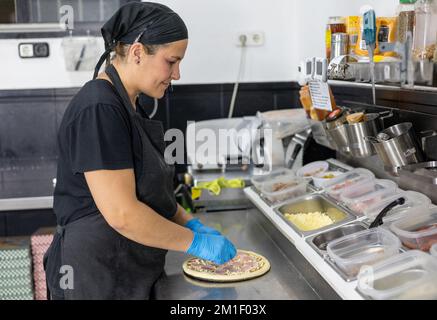 Chefköchin, die Pizza in der Restaurantküche zubereitet Stockfoto