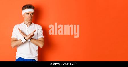 Konzept von Sport, Fitness und Lifestyle. Porträt eines ernsthaft aussehenden männlichen Trainers mit Kreuzzeichen, zu sagen, zu stoppen, etwas zu verbieten und auszudrücken Stockfoto