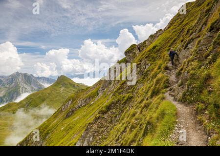 Ein Wanderer wandert auf einem steilen Hang entlang des Gehrengrat. Lech, Österreich, Europa Stockfoto