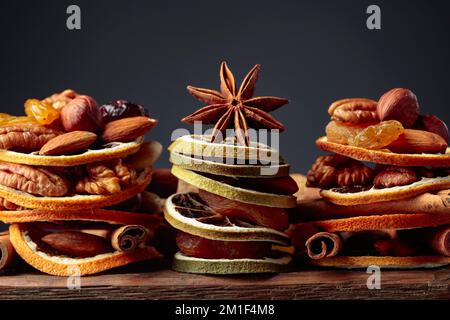 Weihnachtliches Stillleben mit getrockneten Früchten, Nüssen und Gewürzen auf einem alten Holztisch. Speicherplatz kopieren. Stockfoto