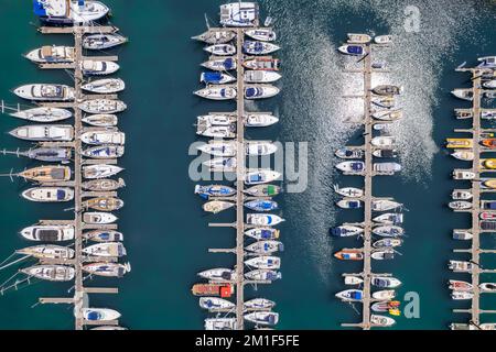 Blick von oben auf weiße Boote und Yachten, die im Yachthafen vor Anker liegen. Stockfoto