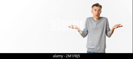 Bild von verwirrten Mann mittleren Alters zuckend Schultern, Blick ahnungslos auf die Kamera, stehend über weißem Hintergrund Stockfoto