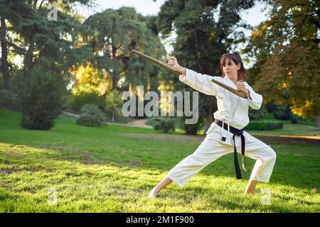 Kampfsportlehrer in weißem Kimono übt mit Tonfa. Hochwertiges Foto Stockfoto