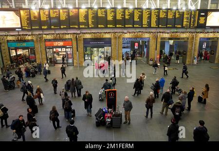 Ein Blick auf Pendler, die auf eine Informationstafel am Bahnhof King's Cross in London blickten, während am Montag in weiten Teilen Großbritanniens Reisetaos herrschten, da Eis, Nebel und Schnee nach der kältesten Nacht des Jahres zu Störungen führten. Foto: Montag, 12. Dezember 2022. Stockfoto