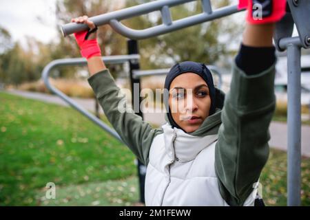 Junge muslimische Frau im Sport-Hijab, die auf dem Outdoor-Trainingsgelände trainiert. Stockfoto