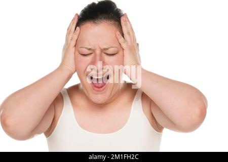 Schockierte panische junge, dicke weiße Frau mit weißem Hintergrund, die Hände am Kopf hält und schreit. Stockfoto