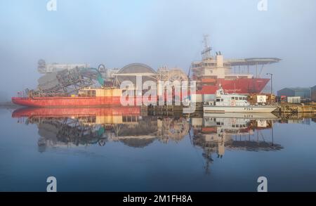 Leith, Edinburgh, Schottland, Großbritannien, 12.. Dezember 2022. Wetter im Vereinigten Königreich: Sonnenschein und Nebel. An einem bitterkalten Tag, an dem die Temperatur nicht über Null Grad steigt, scheint die Sonne mit eiskaltem Nebel, der den Blick über den Hafen verdeckt, und es wird ein Technip-Offshore-Versorgungsschiff im stillen Wasser des Hafens reflektiert. Kredit: Sally Anderson/Alamy Live News Stockfoto