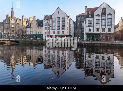 Leith, Edinburgh, Schottland, Großbritannien, 12.. Dezember 2022. Wetter im Vereinigten Königreich: Sonnenschein und Nebel. An einem bitterkalten Tag, an dem die Temperatur nicht über Null Grad steigt, scheint die Sonne auf das Wasser von Leith mit bunten Reflexionen der alten Gebäude im stillen Fluss. Kredit: Sally Anderson/Alamy Live News Stockfoto