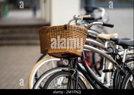 Fahrradkörbe aus Korbgeflecht aus nächster Nähe. Eine Reihe von Leihfahrrädern, die auf einer Stadtstraße geparkt sind. Stockfoto