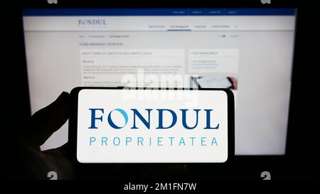 Person, die ein Smartphone mit dem Logo des rumänischen Unternehmens Fondul Proprietatea S.A. auf dem Bildschirm vor der Website hält. Konzentrieren Sie sich auf das Display des Telefons. Stockfoto