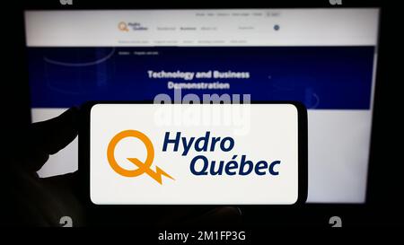Person, die ein Smartphone mit dem Logo des kanadischen Utilityunternehmens Hydro-Quebec auf dem Bildschirm vor der Website hält. Konzentrieren Sie sich auf das Display des Telefons. Stockfoto