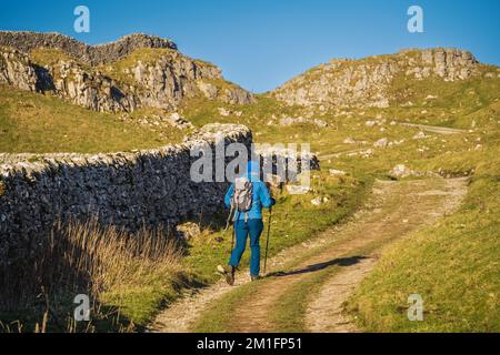 09.12.22 Stainforth, North Yorkshire, Großbritannien. Ein Mann in blauer Kleidung, der in der Wintersonne über Stainforth in den Yorkshire Dales spaziert Stockfoto