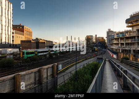 Ein Zug fährt zur Victoria Station, eine frisch renovierte Battersea Power Station ist in der Ferne zu sehen.London Dez. 2022. Stockfoto