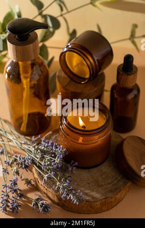 Sojalkerzen in einem Glas. Aromatherapie. Brennende Kerze und Lavendel. Deckel aus Holz für Gläser. Beigefarbener Hintergrund. Komfort und Entspannung. Handgefertigt. Inneneinrichtung. Stockfoto