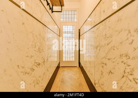 Ein langer Flur mit weißem Marmor an den Wänden und Holzverkleidung um die Wand herum, damit es wie ein Art Deco aussieht Stockfoto