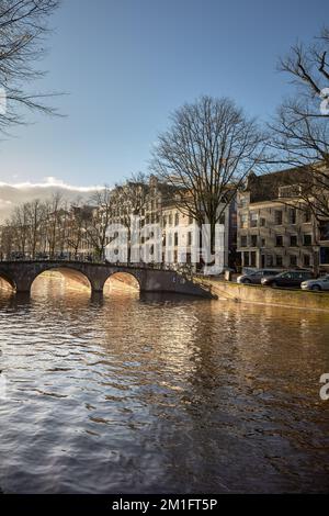 Warme Wintersonne in Amsterdam. Blick auf den Keizersgracht-Kanal mit Blick nach Süden auf die Brücke bei Reestraat. Stockfoto