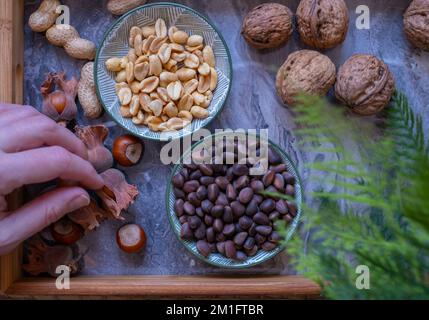Eine Vielzahl von Nüssen in Schalen von oben. Walnüsse, Haselnüsse, Erdnüsse und Pinienkerne, gemischte Auswahl. Gesundes Fitness Super Food Stockfoto