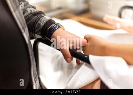 Eine kranke Frau, die sich einer Operation unterziehen wird und die Hand ihres Mannes hält Stockfoto