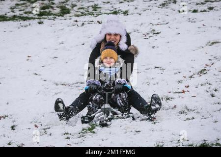 London, Großbritannien. 12.. Dezember 2022. Die Leute im Greenwich Park haben Spaß im Schnee mit den vielen schneebedeckten Hügeln des Royal Park, die viel Platz für Wanderer und diejenigen bieten, die Schlitten fahren, Rodeln und sogar Snowboard fahren wollen. Kredit: Imageplotter/Alamy Live News Stockfoto
