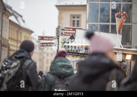 PRAG, Tschechische Republik – DEZEMBER 12. 2022: Gebratener Kastanienstand auf dem Wenzelsplatz in der Weihnachtszeit, Winterschnee, Touristengruppe vor dem Hotel Stockfoto