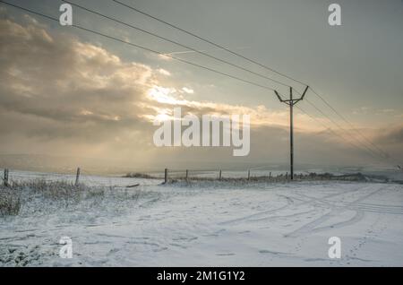 Ditchling, Brighton, East Sussex, Großbritannien. 12.. Dezember 2022. Blick von der Straße zum Ditchling Beacon, wenn die Sonne hinter den Wolken abgeht. Bis zu 5cm m Schnee fielen in einigen Gegenden über Nacht und viele Autofahrer waren gestrandet. Kredit: David Burr/Alamy Live News Stockfoto