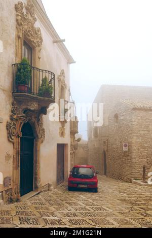 Ein Steinplatz in Erice mit einem roten Auto. Stockfoto