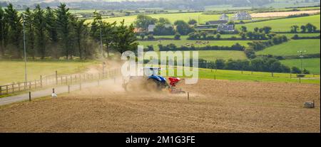 County Cork, Irland, 20. August 2022. Ein blauer Traktor sät an einem Sommertag in Irland ein gepflügtes Feld. Landwirtschaftliche Arbeit auf einem irischen Hof, landwirtschaftlich Stockfoto