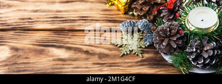 Weihnachtsdekorationen aus Kerzen und Kiefernzapfen, Schneeflocken, grünen Zweigen des Weihnachtsbaums auf einem Holztisch. Banner Stockfoto