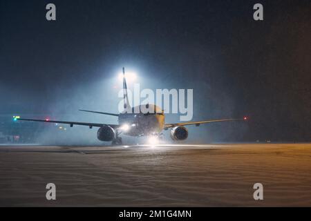 Winternacht am Flughafen. Das Flugzeug rollt bei starkem Schneefall zur Startbahn. Stockfoto