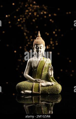 Buddha-Statue in der Meditation auf schwarzem Hintergrund. Vertikales Format. Stockfoto