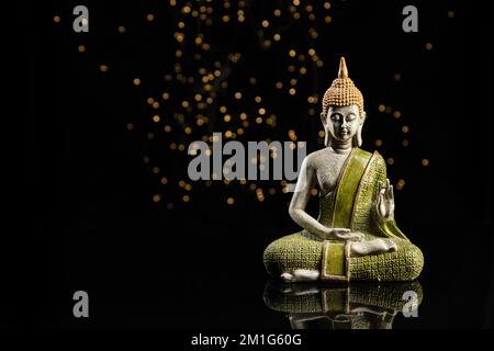 Buddha-Statue in der Meditation mit Lichtern auf schwarzem Hintergrund und Kopierbereich. Stockfoto