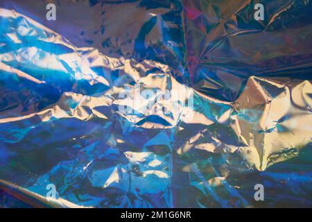 Unfokussierte holografische Farben der Perlmutt-Folie. Verschwommener holographischer abstrakter Hintergrund in Blautönen. Holographischer, schillernder abstrakter Hintergrund aus Regenbogenfolie. Hochwertige Fotos Stockfoto