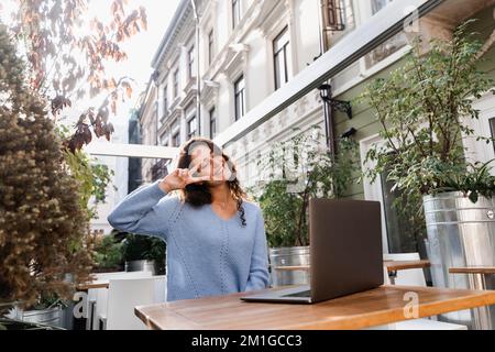 Eine Bloggerin mit Laptop chattet online über eine Videoverbindung mit ihren Abonnenten. Glückliche junge Geschäftsfrau unterhält sich mit Kollegen und hat es getan Stockfoto